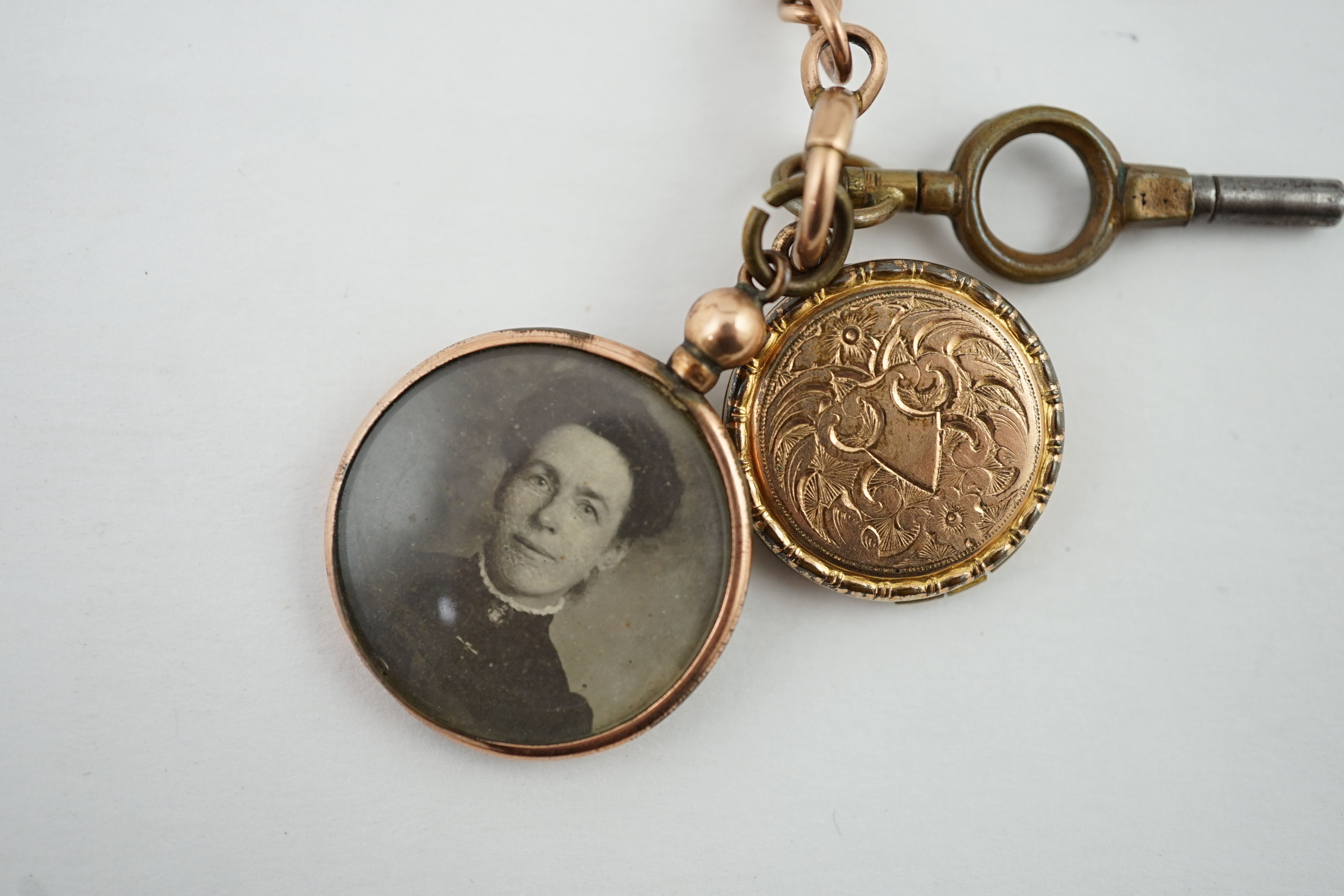 An Edwardian 9ct gold curb link albert, hung with a 9ct gold Masonic charm, locket and a double sided portrait pendant